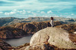 Girl tourist sitting on a rock with a bewitching view of the Norwegian fjord, Norway. Landscape with sporty girl, rocks, Norwegian fjord, blue sky and clouds.Active lifestyle concept.Lifestyle