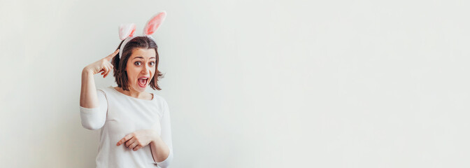 Wall Mural - Happy Easter holiday celebration spring concept. Young woman wearing bunny ears isolated on white background. Preparation for holiday. Girl looking happy and excited, having fun on Easter day. Banner