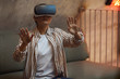 © Seventyfour - Waist up portrait of Asian woman wearing VR gear and gesturing while enjoying immersive experience in futuristic interior, copy space