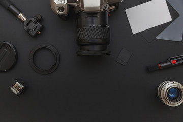 Poster - Photographer workplace with dslr camera system, camera cleaning kit, lens and camera accessory on dark black table background. Hobby travel photography concept. Flat lay top view copy space