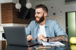 © Drobot Dean - Smiling young bearded man working on laptop computer