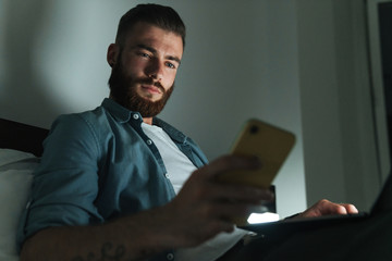 Poster - Smiling young bearded man laying on bed at home