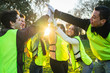 Teamwork - Business team success - Six people with yellow bibs beat high five in the air at the park at sunset after community service - Concept of unity and collaboration