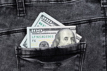 One hundred dollar banknote money in pocket jeans pants background texture. 100 dollar bill close up