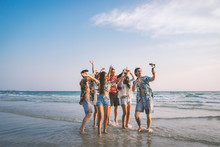 A Group Of Happy Friends Having Enjoy Playing Selfies On The Beach Amid The Blue Sky.