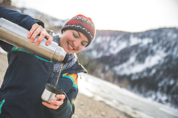 Outdoor wilderness adventure: Caucasian girl is drinking a metal cup of tea