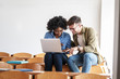 © BalanceFormCreative - In the university classroom, a female and a male student sit side by side, focused on their laptop, diligently preparing for the upcoming lecture.
