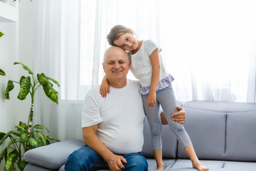 Wall Mural - Portrait Of Grandfather With Granddaughter Relaxing Together On Sofa