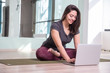© Viktorija - Photo of young woman practicing yoga with laptop indoor. Beautiful girl practice yoga in class. Yoga studio instructor. Blurred background.