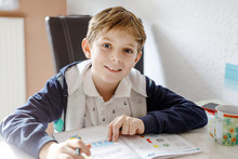 Portrait Of Cute Happy School Kid Boy At Home Making Homework. Little Child Writing With Colorful Pencils, Indoors. Elementary School And Education. Kid Learning Writing Letters And Numbers