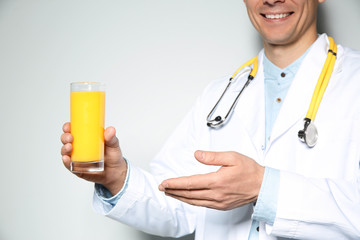 Poster - Nutritionist with glass of juice on light grey background, closeup