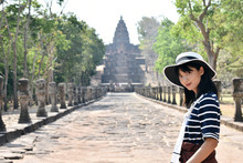 Young Asian Thai Woman Wearing а Striped Shirt And White Hat Posing In Ancient Khmer Civilisation Temple. Prasat Hin Phanom Rung, Thailand