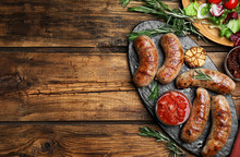 Tasty Grilled Sausages Served On Wooden Table, Flat Lay. Space For Text