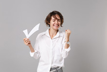 Happy Young Business Woman In White Shirt Posing Isolated On Grey Wall Background In Studio. Achievement Career Wealth Business Concept. Mock Up Copy Space. Hold Paper Check Mark Doing Winner Gesture.