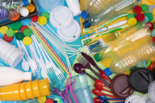 Disposable single use plastic objects such as bottles, cups, forks, spoons and drinking straws that cause pollution of the environment, especially oceans. Top view.