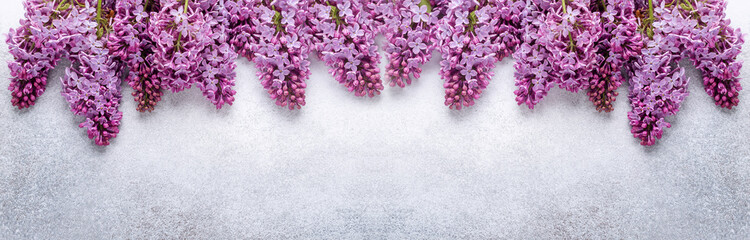 Branches of purple lilac on stone background. Romantic spring mood. Top view. Copy for your text. Horizontal banner