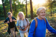 © Halfpoint - Senior women friends with camera walking outdoors in forest.