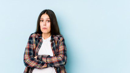 Wall Mural - Young caucasian woman isolated on blue background shrugs shoulders and open eyes confused.