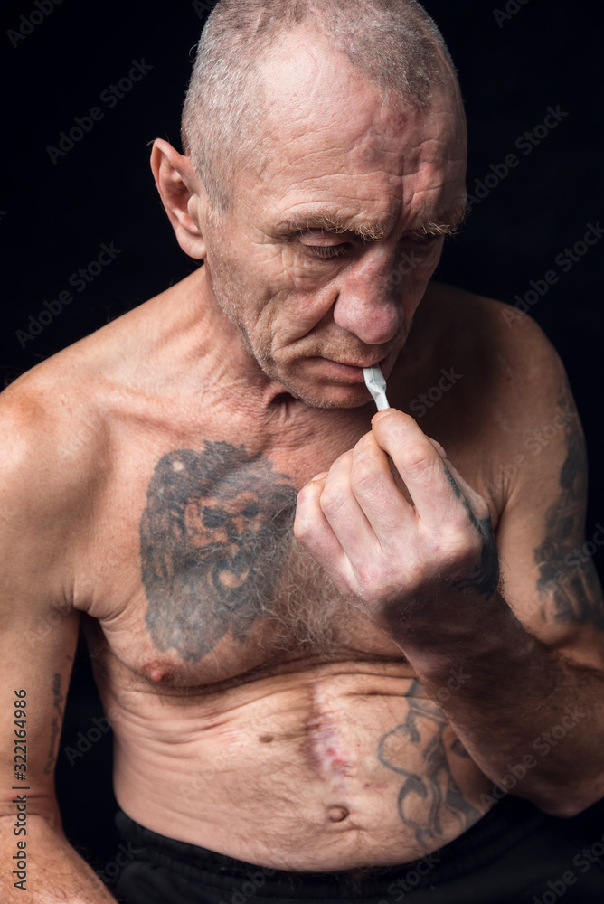 cigarettes and alcohol tattoo Old man alcoholic with tattoos lights a cigarette on a black background  Stock Photo