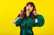 Cheerful gorgeous girl in clothes in the style of the 90s, with a vintage cassette player and headphones, in the studio on a white background. Music, emotions, fashion