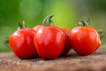 Group of ripened tasty red raw strawberry tomatoes on wood on green natural background, tasty healthy vegetables still life