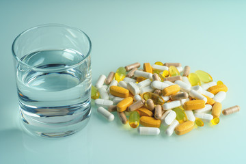 Wall Mural - Medicaments, pill capsules, drugs and dietary supplements with water glass close up. Medication treatment concept.