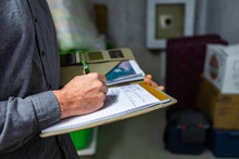 Inspector Holding A Notebook In His Hand During A Home Inspection In The Basement, Close Up And Selective Focus Of A Man Taking Professional Notes.