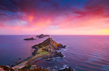 View of Pointe de la Parata on the west coast of Corsica France Europe. A ruined Genoese tower sits on top of the rocky promontory overlooking the archipelago of the Sanguinaires on the colored sunset