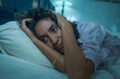 dramatic night lifestyle potrait of young sad and depressed middle eastern woman with curly hair sleepless in bed awake feeling worried suffering depression problem
