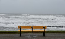 Bench On The Beach Surrounded By The Sea Under A Cloudy Sky During The Storm