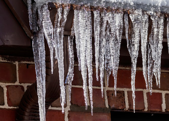 Wall Mural - Ice icicles hanging from a roof gutter