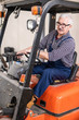 © pressmaster - Serious senior forklift truck driver in glasses loading goods from deliveries at factory