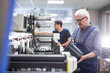 © pressmaster - Serious senior worker with mustache standing at printing press and filling inkjet cartridge with black ink