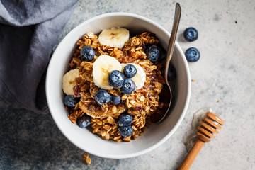 Wall Mural - Homemade granola bowl with blueberries, banana and honey, top view.