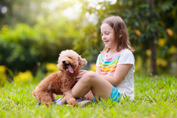 Kids play with puppy. Children and dog in garden.