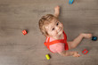 © Lisa Tichané - Cute baby sitting on wooden floor looking up