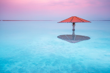 Fototapete - Dead Sea beach. Sun umbrella in water. Minimalist landscape