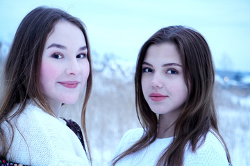 two girls girls in white sweatshirts and openwork shawls on a background of nature