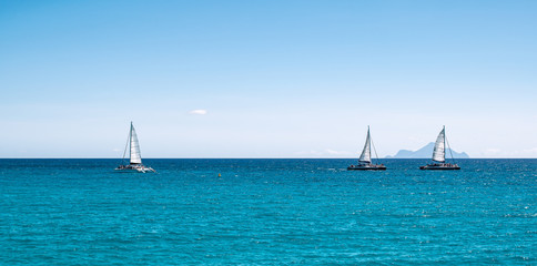 Poster - Panoramic sea view with three sailing boats cruising on the ocean.