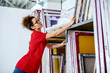 © Dusan Petkovic - Cute caucasian female employee with curly hair and with eyeglasses reaching for silk screen plates. Printing shop interior.
