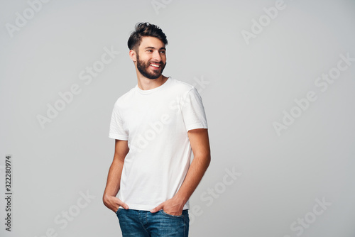 Fotomural Handsome young man smiling isolated on grey background wearing casual t-shirt an