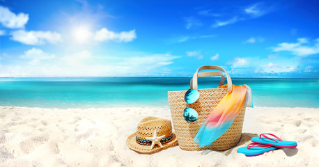Wall Mural - Concept summer holiday. Accessories - bag, straw hat, sunglasses with palm tree reflection, pareo, flip-flops on sandy beach against ocean, blue sky, clouds and bright sun. Beautiful colorful image.