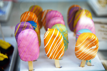 Beautifully decorated ice cream in a pastry shop showcase.  Ice cream on a stick in various colors.