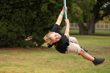 Wall Mural - Happy boy playing on swing at the playground