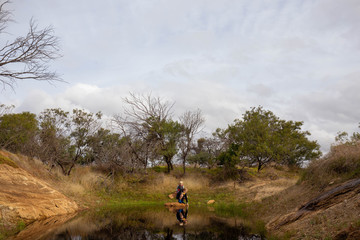 Wall Mural - Two young boys catching tadpoles in natural waterhole