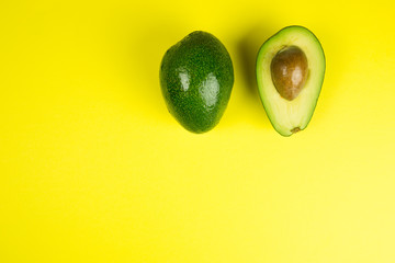 Green fresh avocado on isolated yellow background. Vitamin, vegan food concept