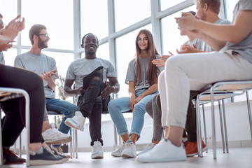 smiling speaker sitting in a circle of young people