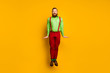 Full length photo of attractive funky guy jumping high up good mood rejoicing wear green shirt red suspenders pants socks footwear isolated yellow color background