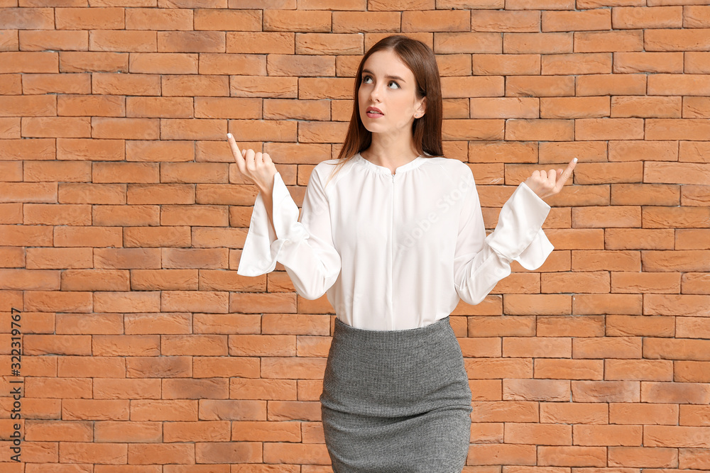 Thoughtful businesswoman against brick wall