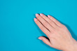 © Andrii Oleksiienko - Closeup top view of one beautiful female hand isolated on blue background.